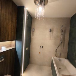 SUNWALL SPÓŁKA Z OGRANICZONĄ ODPOWIEDZIALNOŚCIĄ - Nowoczesna łazienka z kabiną prysznicową, wanną, podwieszaną toaletą i oświetleniem LED w pionowej szczelinie ściennej oraz kryształowym żyrandolem sufitowym.