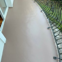 KRIS-STUC Krystian Maczukin - Gładka, beżowa powierzchnia balkonu z kutą, ozdobną balustradą, widok z góry.