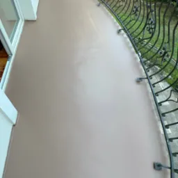 Gładka, beżowa powierzchnia balkonu z kutą, ozdobną balustradą, widok z góry.