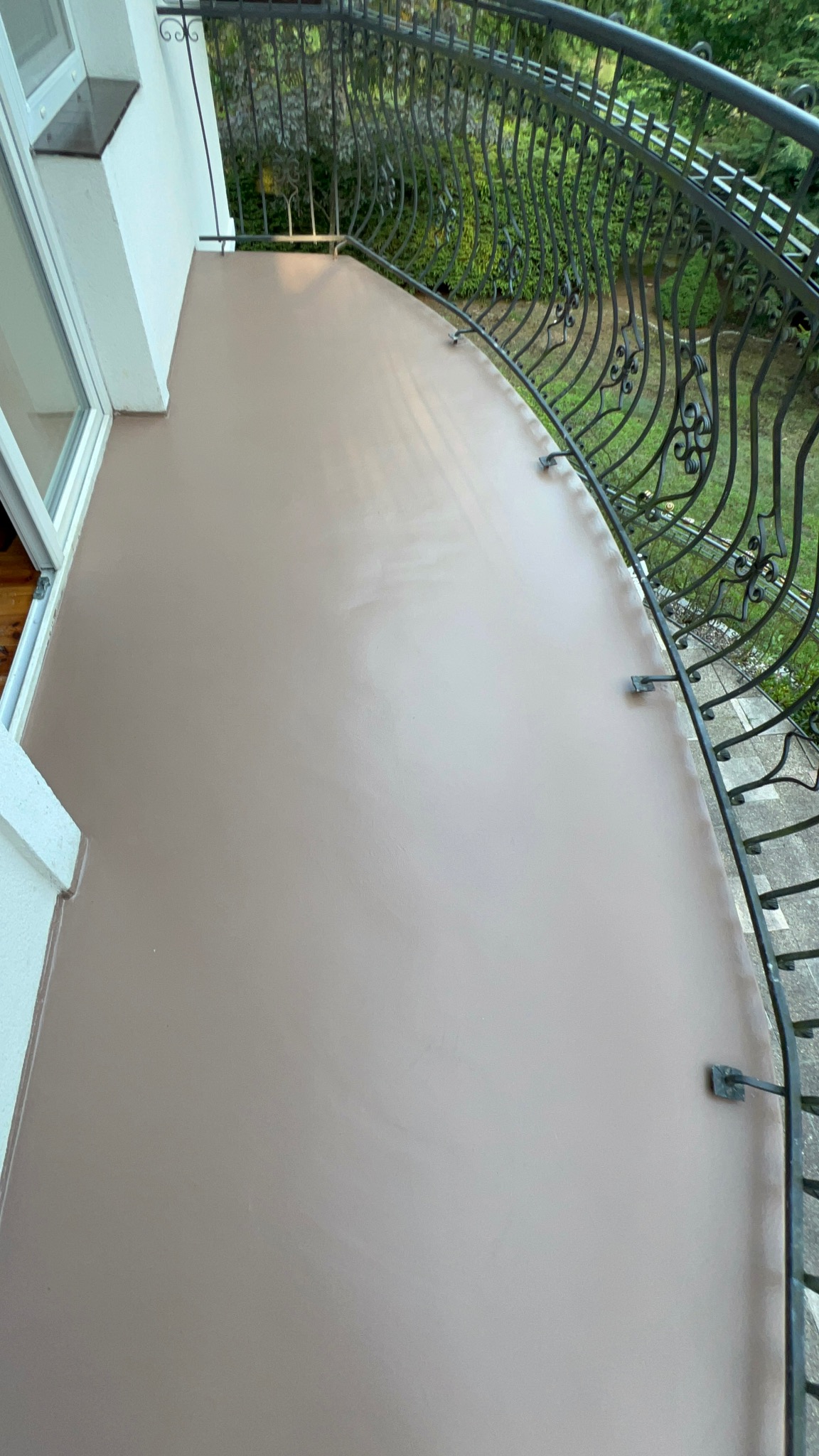 Gładka, beżowa powierzchnia balkonu z kutą, ozdobną balustradą, widok z góry.