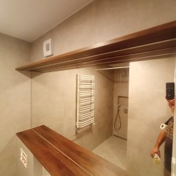 FERMONT USŁUGI BUDOWLANE Wojciech Nowak - Wykończona łazienka z drewnianym blatem nad umywalką, grzejnikiem drabinkowym i kabiną prysznicową z odpływem liniowym w podłodze, widoczne płytki w odcieniach szarości oraz drewniana półka...