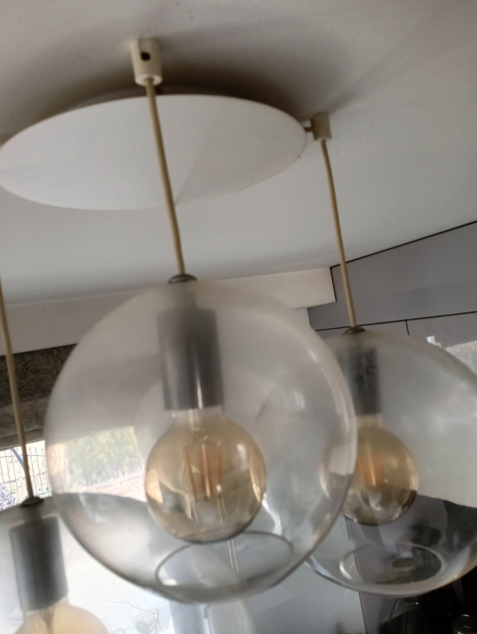 Szklane lampy wiszące w stylu retro z żarówkami Edisona, zamontowane na suficie w mieszkaniu w Olsztynie, widoczne drobne zabrudzenia na kloszach.