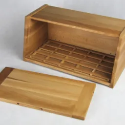 Otwarty chlebak z jasnego drewna z wyjmowaną deską do krojenia, widoczne detale konstrukcyjne i naturalne usłojenie drewna na białym tle.