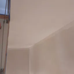 Świeżo położony, gładki tynk na ścianach i suficie w narożniku pomieszczenia, widoczne ślady po taśmie malarskiej przy framudze drzwi.