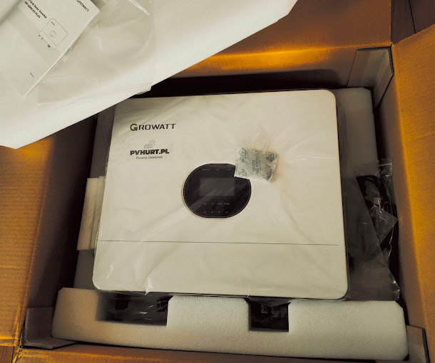 Nowy, biały falownik Growatt w kartonowym opakowaniu, zabezpieczony folią i pianką, widoczna naklejka PVhurt.pl oraz instrukcja obsługi.