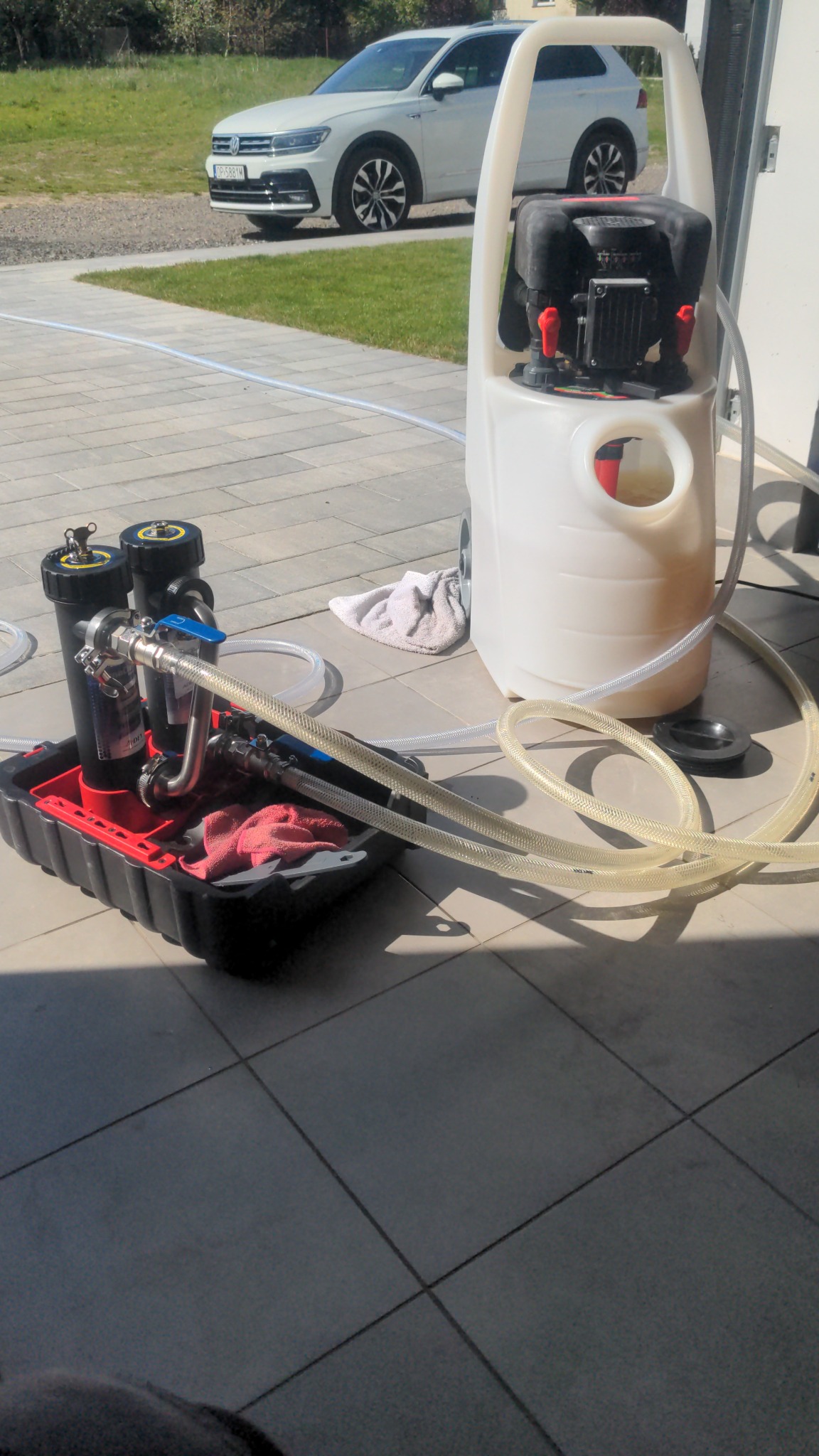 Profesjonalny sprzęt do czyszczenia instalacji CO z filtrami i pompą, na zewnątrz, z widocznym samochodem w tle.