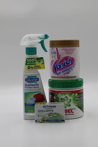 Zestaw środków do usuwania plam i prania: spray Dr. Beckmann, Vanish Oxi Advance, Ariel i mydło galasowe Heitmann, ustawione na białym tle.