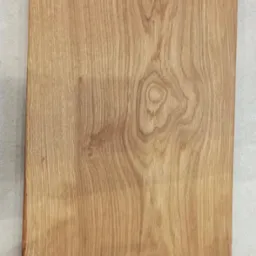 Prostokątna, dębowa deska do krojenia z widocznym usłojeniem drewna, leżąca na szarych płytkach podłogowych.