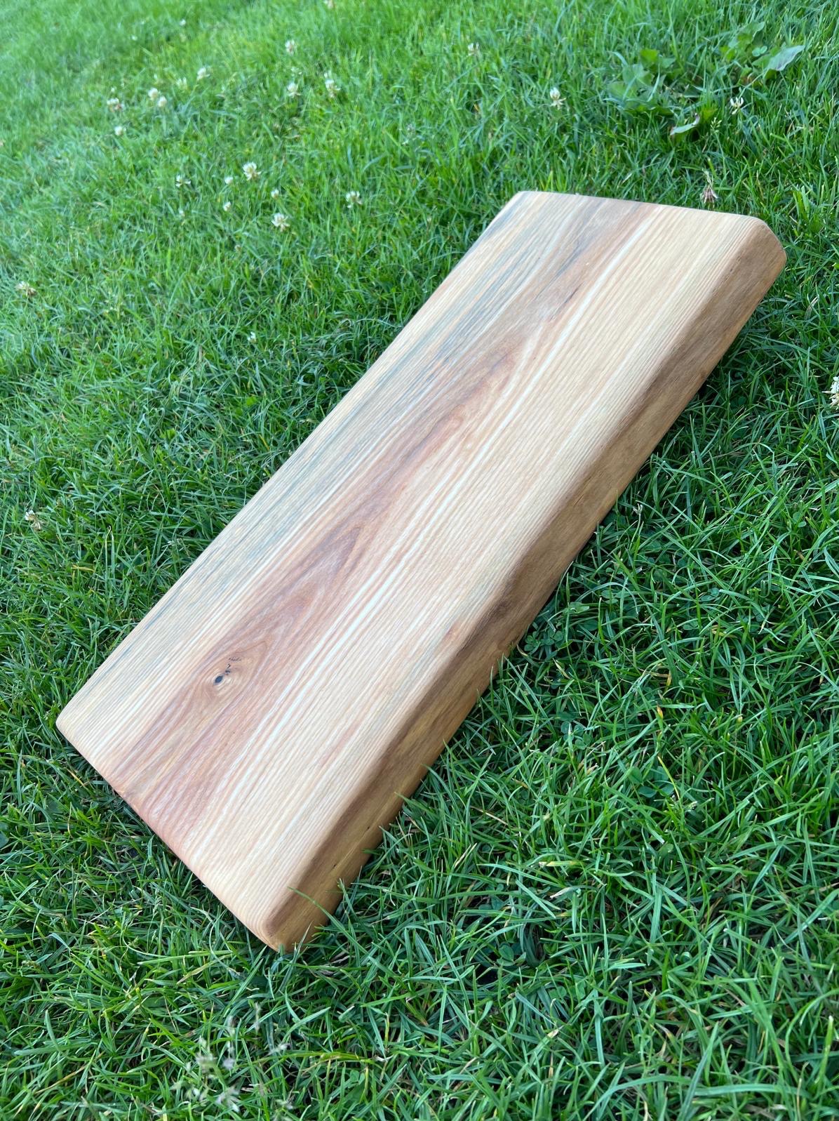 Jesionowa deska do serwowania, zabezpieczona olejem do kontaktu z żywnością, leżąca na trawie.