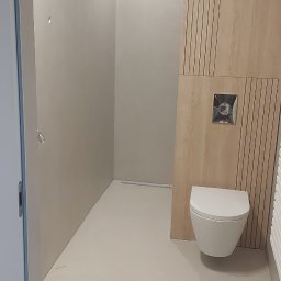 DJ art floor & walls - Minimalistyczna łazienka z mikrocementową podłogą, drewnianą boazerią i podwieszaną toaletą. Widoczny odpływ liniowy w podłodze.