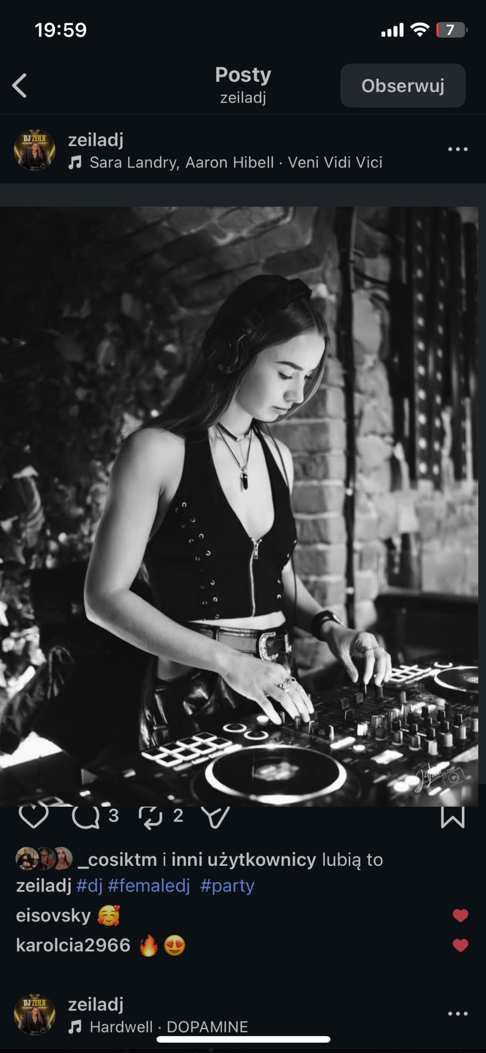 Czarno-białe zdjęcie DJ-ki w trakcie występu, skupionej na miksowaniu muzyki przy użyciu profesjonalnego sprzętu. W tle widoczna ceglana ściana.