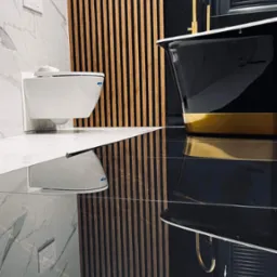 Elegancka łazienka z czarną wanną wolnostojącą z złotym akcentem, złotą baterią, wiszącą toaletą i dekoracyjnymi drewnianymi lamelami na ścianie z białego marmuru, odbicie elementów w polerowanej...