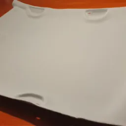 Jasnoszara podsufitka samochodowa z widocznymi otworami montażowymi, leżąca na pomarańczowym podłożu.