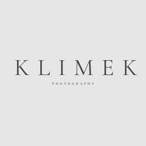 Minimalistyczne logo firmy fotograficznej: ciemnoszary napis 'KLIMEK' nad słowem 'PHOTOGRAPHY' na jasnoszarym tle. Elegancki font.