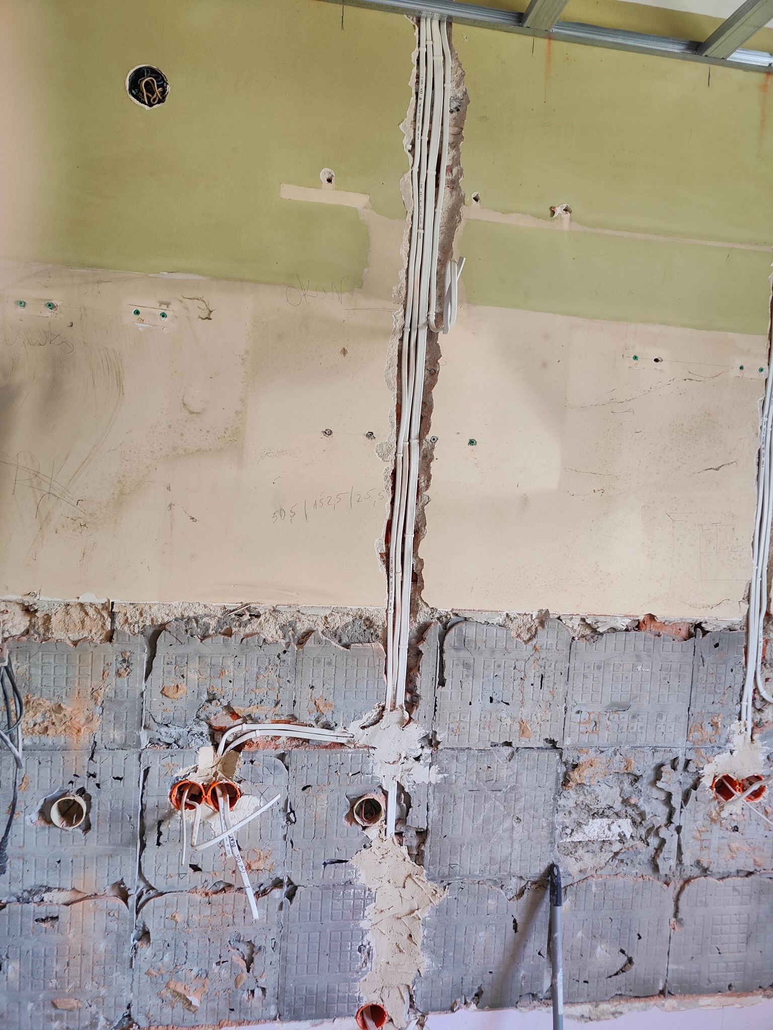 Ściana w trakcie remontu z widoczną instalacją elektryczną w peszlach i przewodach, przygotowana do położenia tynku.