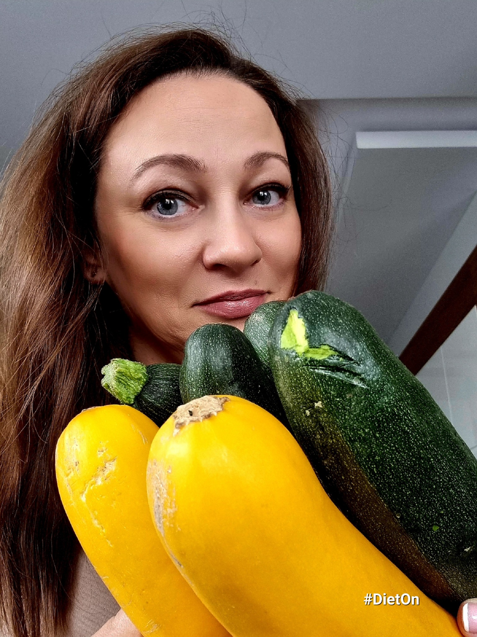 Kobieta z Piotrków Trybunalski trzymająca w dłoniach świeże, żółte i zielone cukinie. Jedna z zielonych cukinii ma widoczne uszkodzenie skórki.