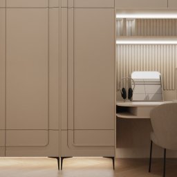 ANETA WIELGOSZ ARTENEUM PRACOWNIA ARCHITEKTONICZNA - Beżowe biurko z szafkami w pokoju, oświetlone półki, słuchawki, kalendarz i krzesło. Minimalistyczny design, ciepłe światło, drewniana podłoga.