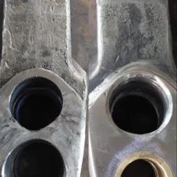 Porównanie elementu metalowego przed i po obróbce: po lewej stronie surowy, z widocznymi śladami obróbki, po prawej oszlifowany i z zamontowaną tuleją z brązu.