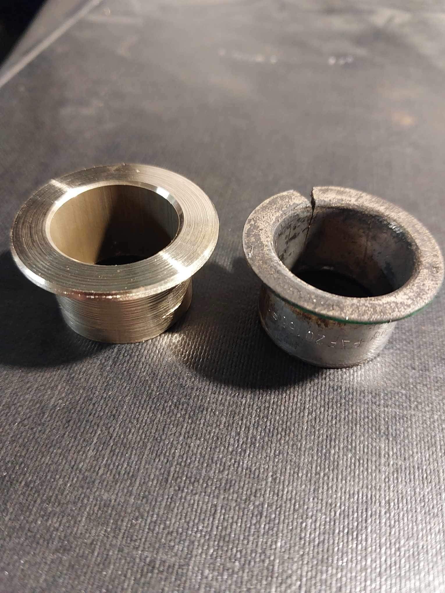 Porównanie dwóch tulei: nowej, mosiężnej z widocznymi śladami obróbki tokarskiej oraz zużytej, pękniętej tulei z inskrypcjami.
