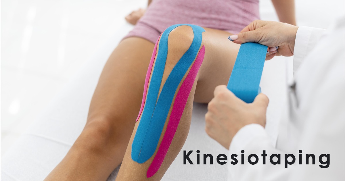 Nakładanie elastycznych taśm kinezjologicznych w kolorach niebieskim i różowym na kolano pacjenta przez osobę w białym fartuchu medycznym.
