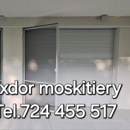 Exdor rolety żaluzje plisy moskitiery - Zamontowane moskitiery ramkowe w kolorze białym na tarasie, częściowo zasłonięte opuszczonymi roletami zewnętrznymi, widoczny numer telefonu firmy Exdor.