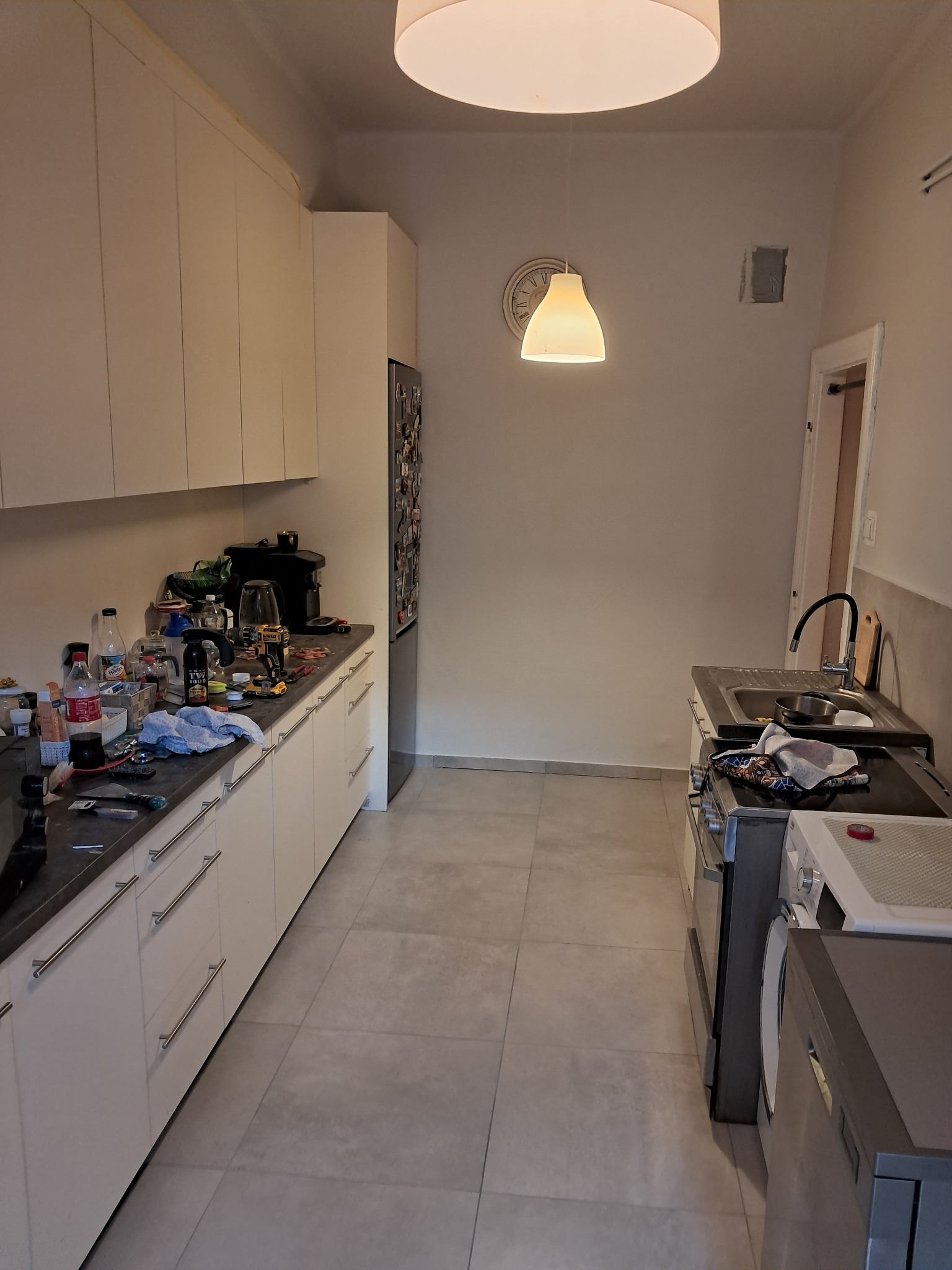 Wnętrze kuchni w trakcie remontu, z widocznymi narzędziami i materiałami budowlanymi na blacie, ściany przygotowane do dalszych prac wykończeniowych.