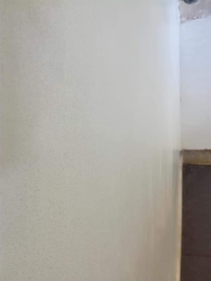 Świeżo położona, jasna gładź szpachlowa na ścianie w rogu pomieszczenia, widoczne delikatne nierówności i struktura.