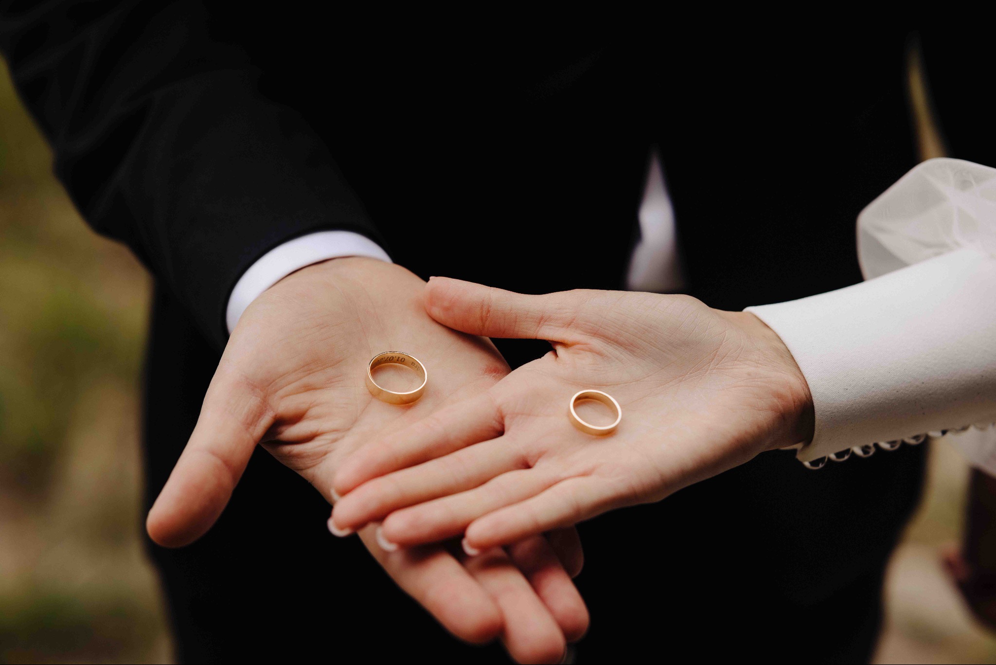 Dłonie pary młodej z obrączkami ślubnymi; na jednej obrączce widoczny grawer z datą 10.07.