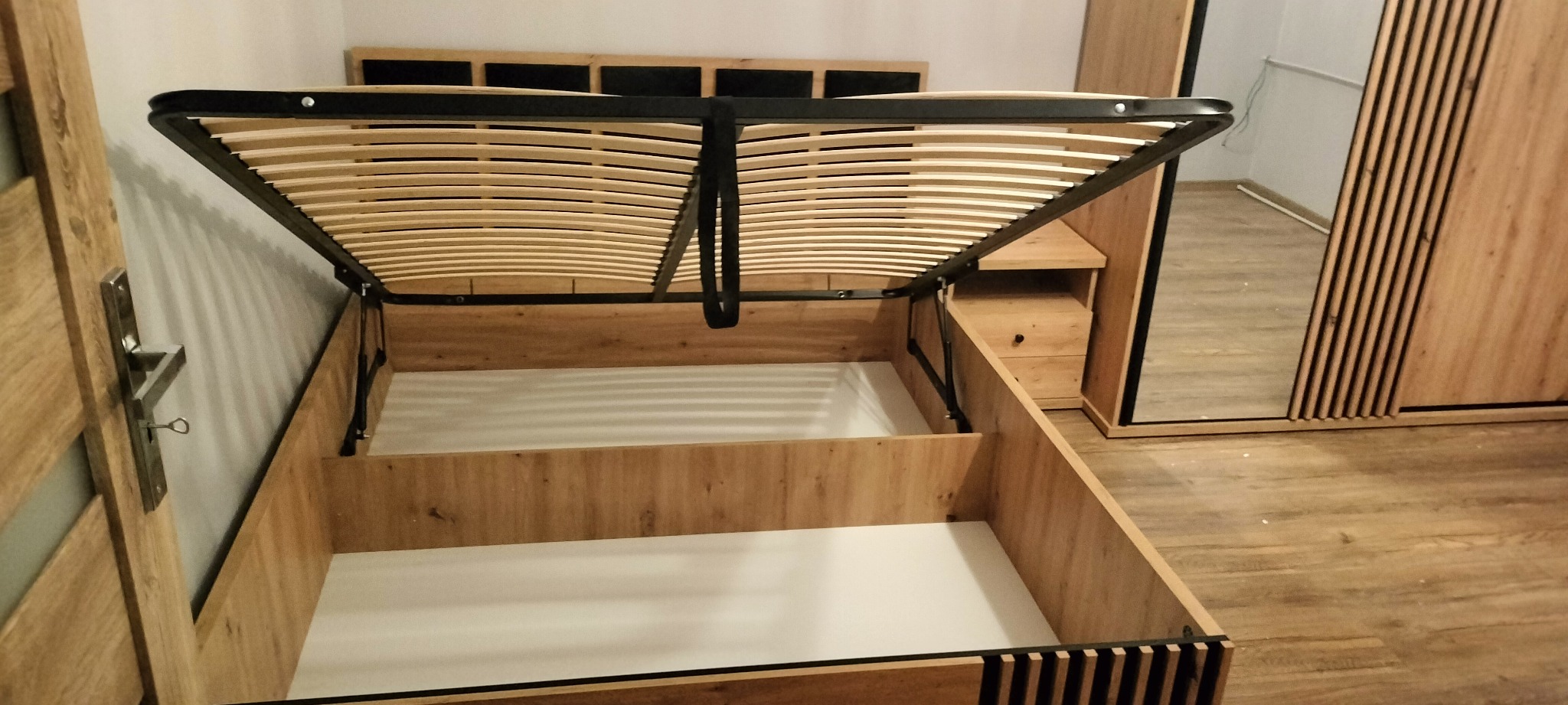 Łóżko z podnoszonym stelażem w sypialni w Nowej Rudzie, widoczny mechanizm podnoszenia i pojemnik na pościel, w tle szafa z lustrem.