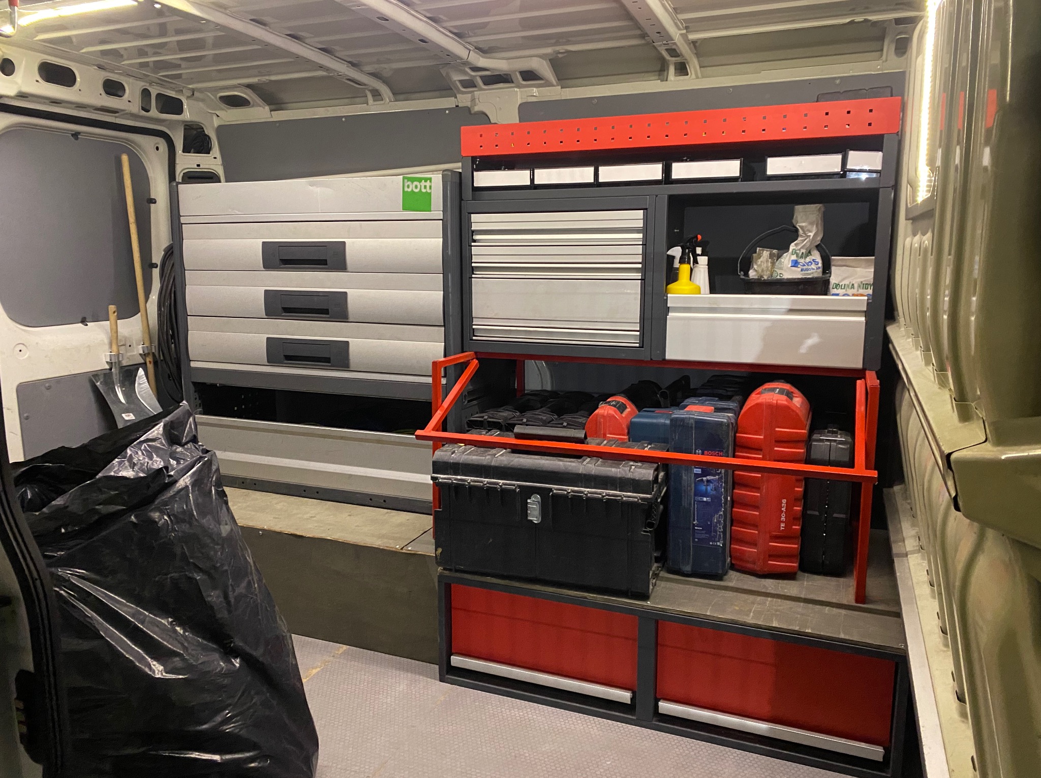 Wnętrze furgonetki elektryka z szufladami narzędziowymi Bott, skrzynkami na narzędzia Bosch i workiem na śmieci, gotowe do pracy.