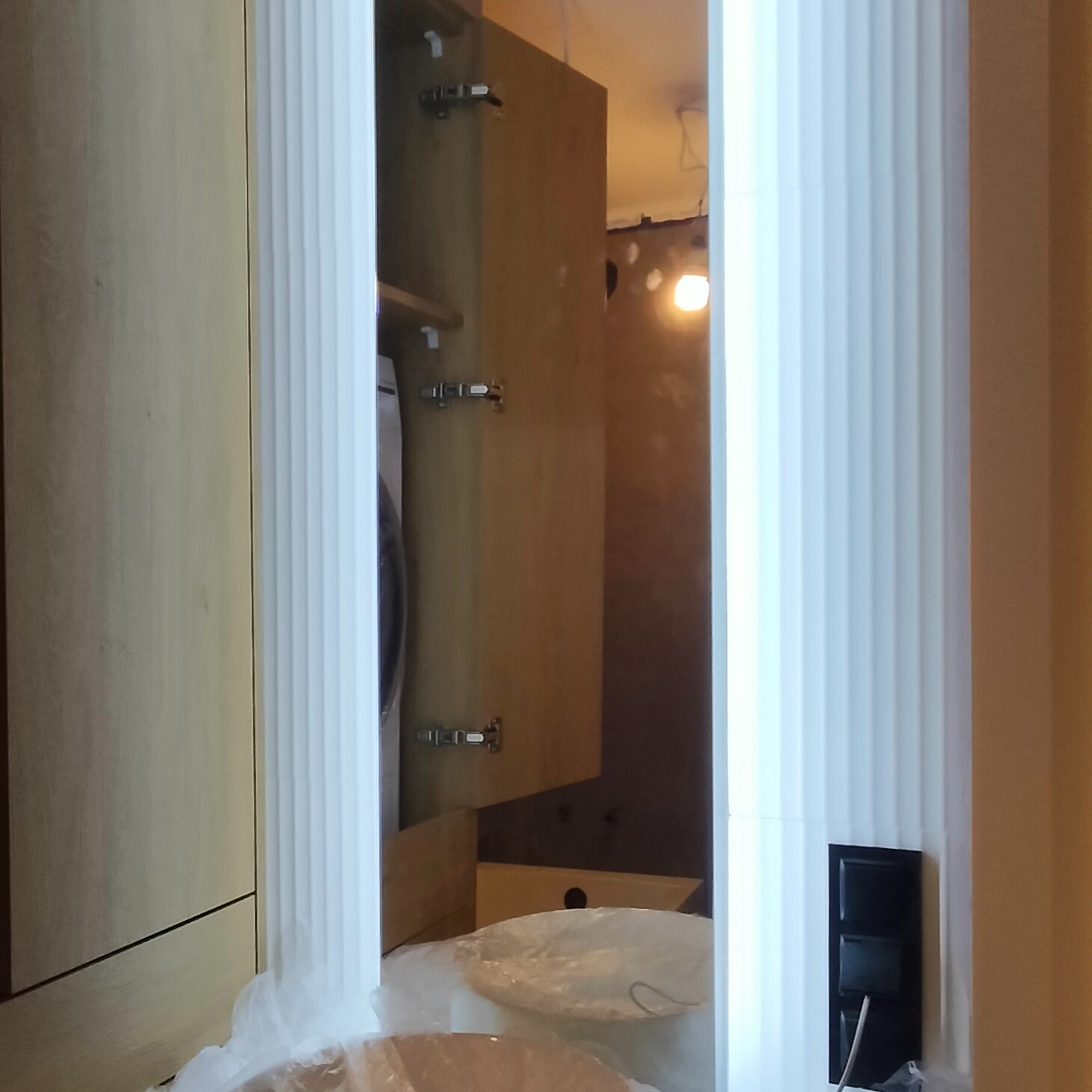 Wnętrze szafki z zamontowanym oświetleniem LED, widoczne kable i elementy instalacji elektrycznej w trakcie prac wykończeniowych.