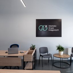 GGK Sp. z o.o. - Nowoczesne biuro rachunkowe z logo 'Gdańska Grupa Księgowych' na ścianie, biurkiem z laptopem i minimalistycznym wystrojem. Stonowana kolorystyka, rośliny doniczkowe.