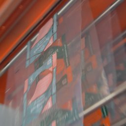 “ZEW-GRAND” PRZEDSIĘBIORSTWO PRODUKCYJNO HANDLOWE SPÓŁKA Z OGRANICZONĄ ODPOWIEDZIALNOŚCIĄ - Automatyczna linia pakująca worki z keramzytem, widoczne detale etykiet i zgrzewów na folii, pomarańczowe elementy konstrukcyjne maszyny w tle.