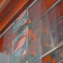 Automatyczna linia pakująca worki z keramzytem, widoczne zamazane etykiety produktu w foliowych opakowaniach na tle pomarańczowej konstrukcji maszyny.