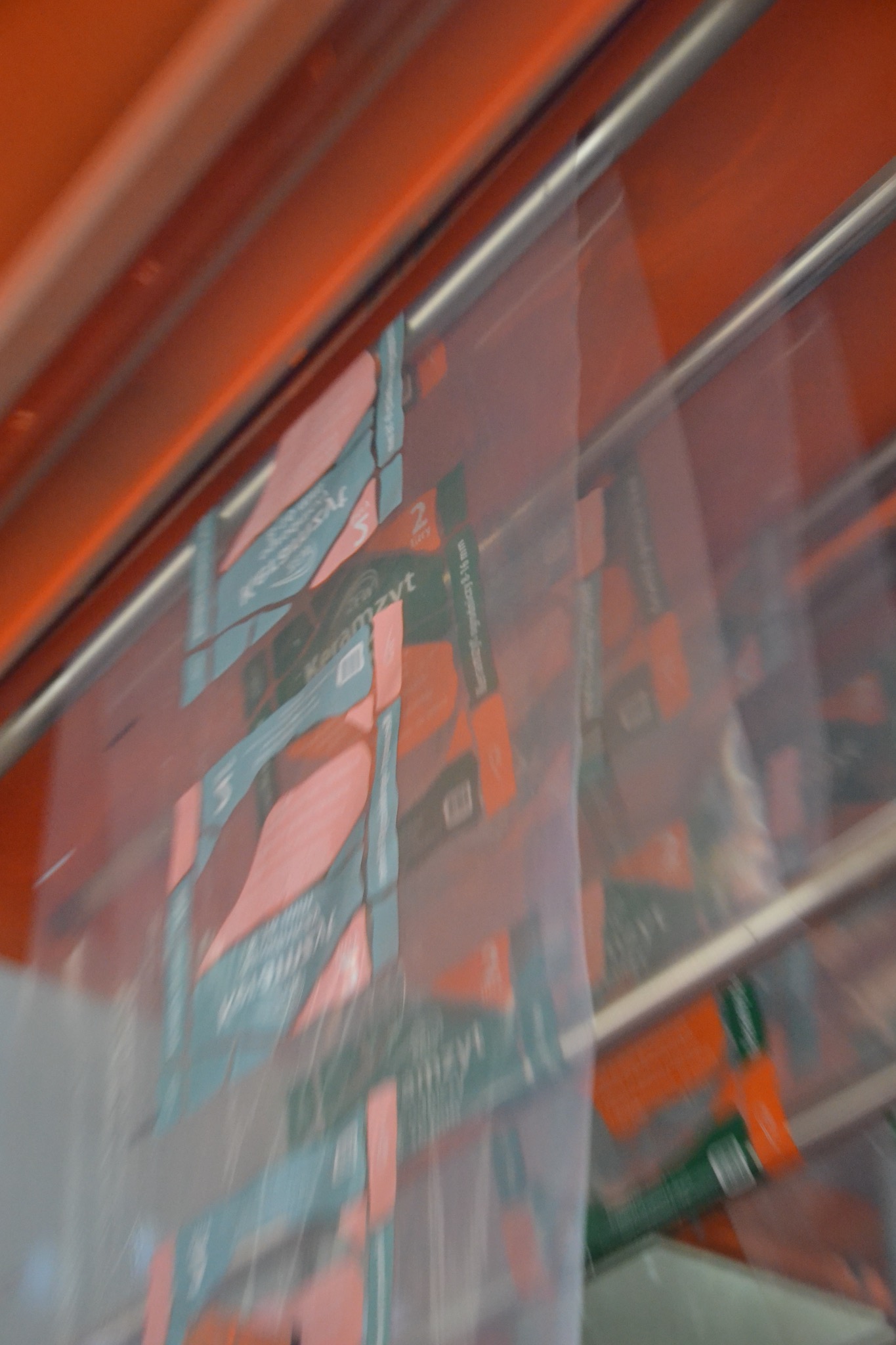 Automatyczna linia pakująca worki z keramzytem, widoczne detale etykiet i zgrzewów na folii, pomarańczowe elementy konstrukcyjne maszyny w tle.