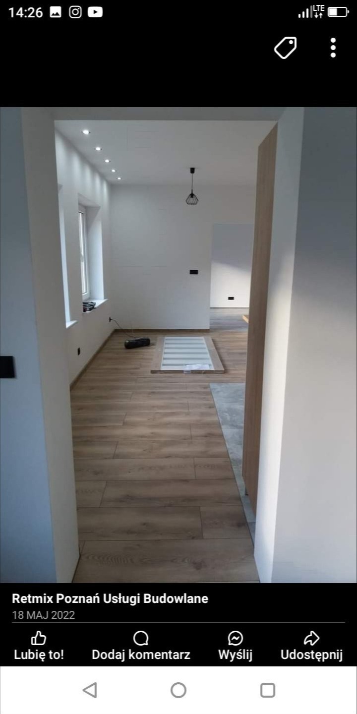 Wnętrze po remoncie: parkiet w odcieniach brązu, białe ściany z punktowym oświetleniem sufitowym i wiszącą lampą, widoczny fragment drzwi i okna, na podłodze leżą panele podłogowe przygotowane...