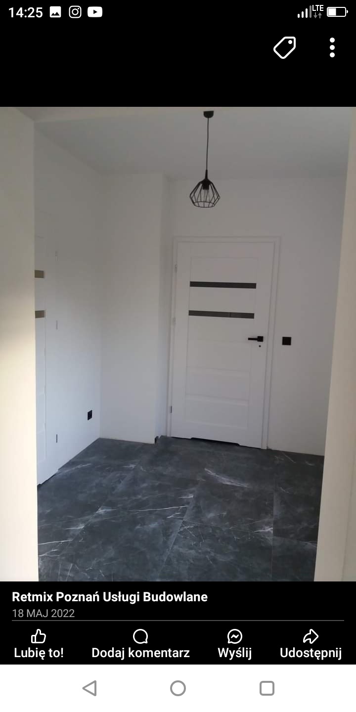 Wnętrze po odświeżeniu: białe ściany, ciemna marmurkowa podłoga, nowoczesna biała drzwi z czarnymi akcentami i designerska lampa wisząca.