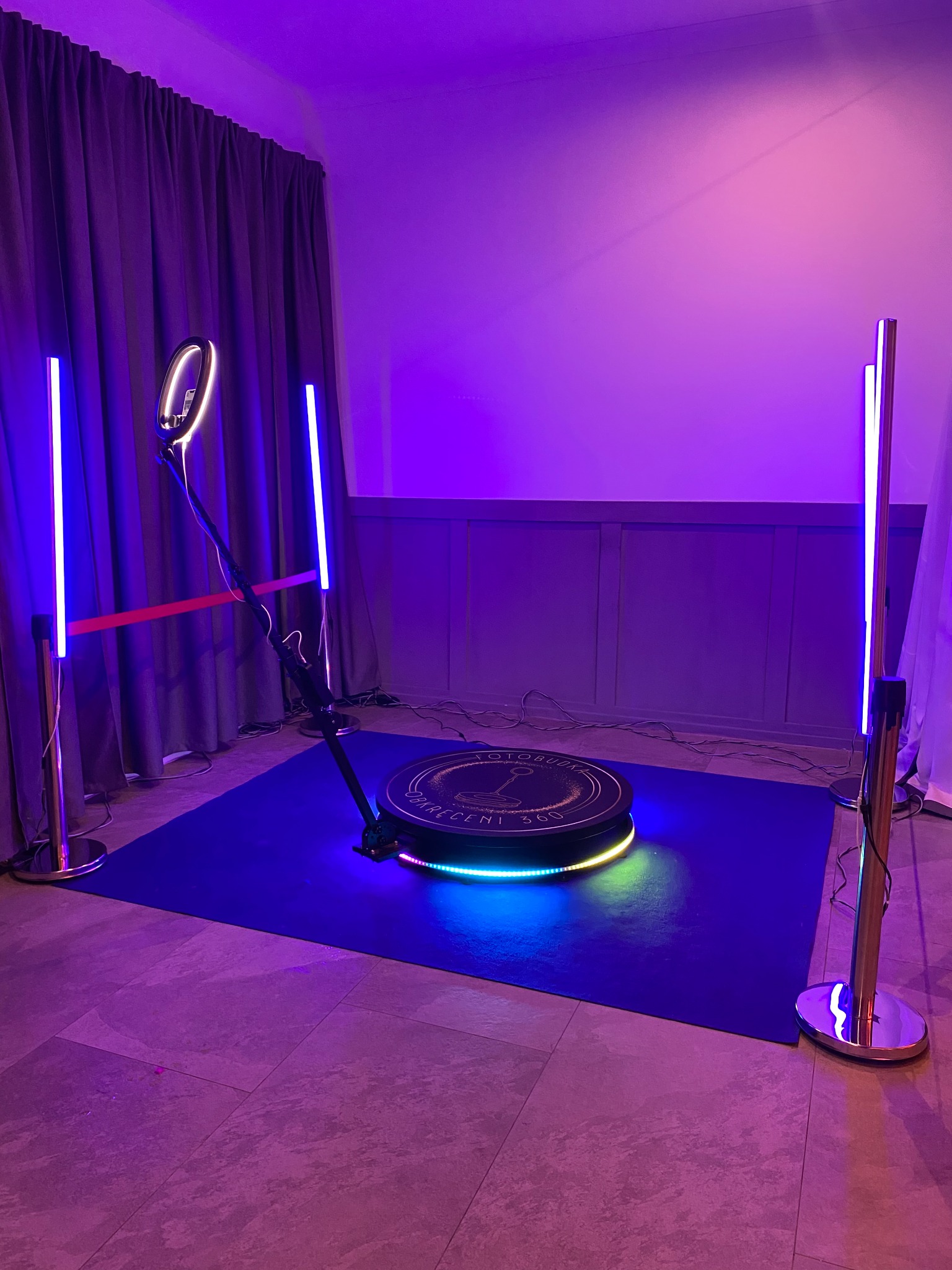 Oświetlona platforma obrotowa 360 z barierkami i ringiem świetlnym, ustawiona na ciemnoniebieskim dywanie, w pomieszczeniu z fioletowym oświetleniem.
