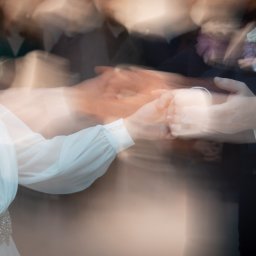 Rafał Torbicki Fotografia - Rozmyte ujęcie dłoni pary młodej podczas pierwszego tańca, widoczny pierścionek na palcu panny młodej, bukiet w butonierce pana młodego i fragment sukni.