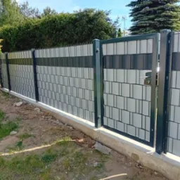 Nowoczesne ogrodzenie panelowe z podmurówką betonową i furtką, widoczne na tle zieleni. Szare panele z poziomym pasem grafitowych elementów.