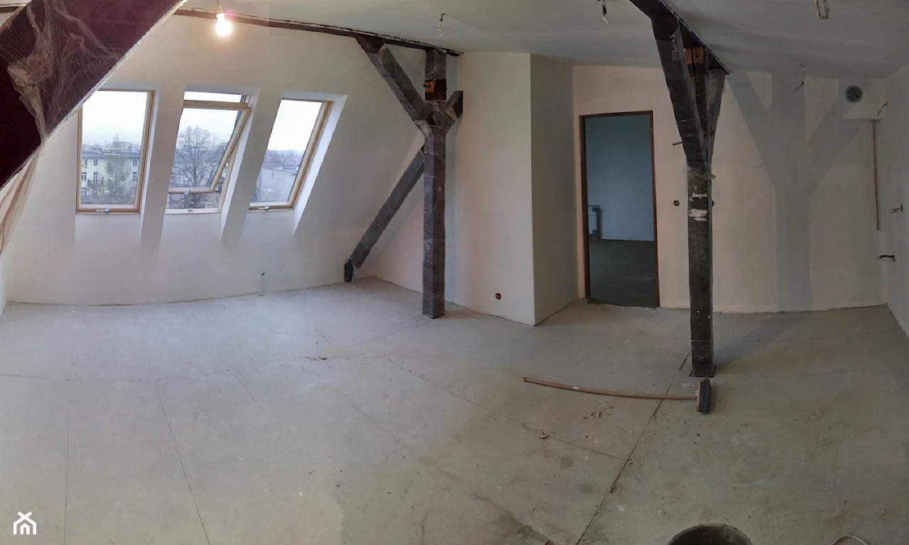 Poddasze w trakcie prac wykończeniowych: surowe ściany, okna dachowe, zabezpieczone folią drewniane elementy konstrukcyjne, betonowa wylewka na podłodze, widoczne instalacje elektryczne.