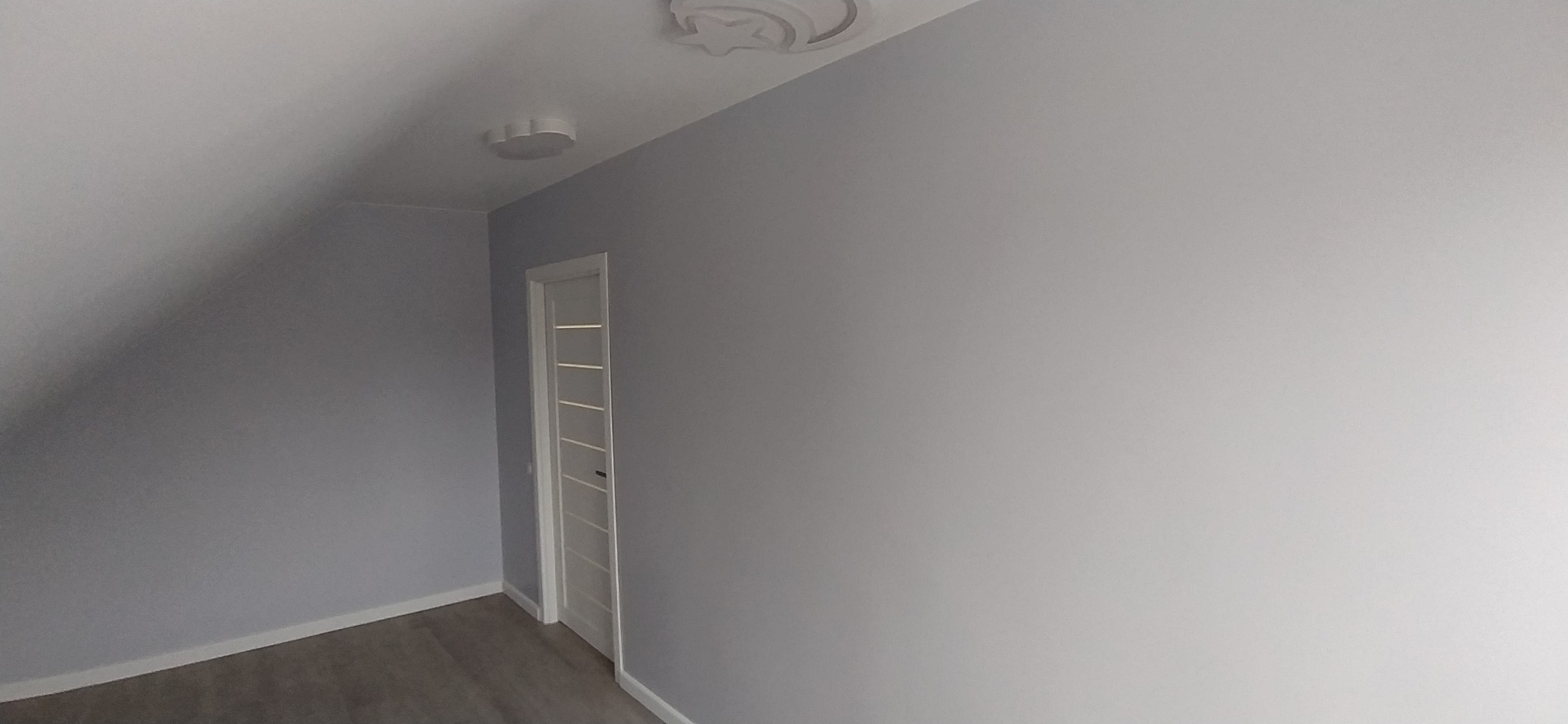 Pokój na poddaszu po odświeżeniu, ściany pomalowane na szaro, białe drzwi z przeszkleniami, dwa okrągłe plafony i jeden w kształcie gwiazdy.