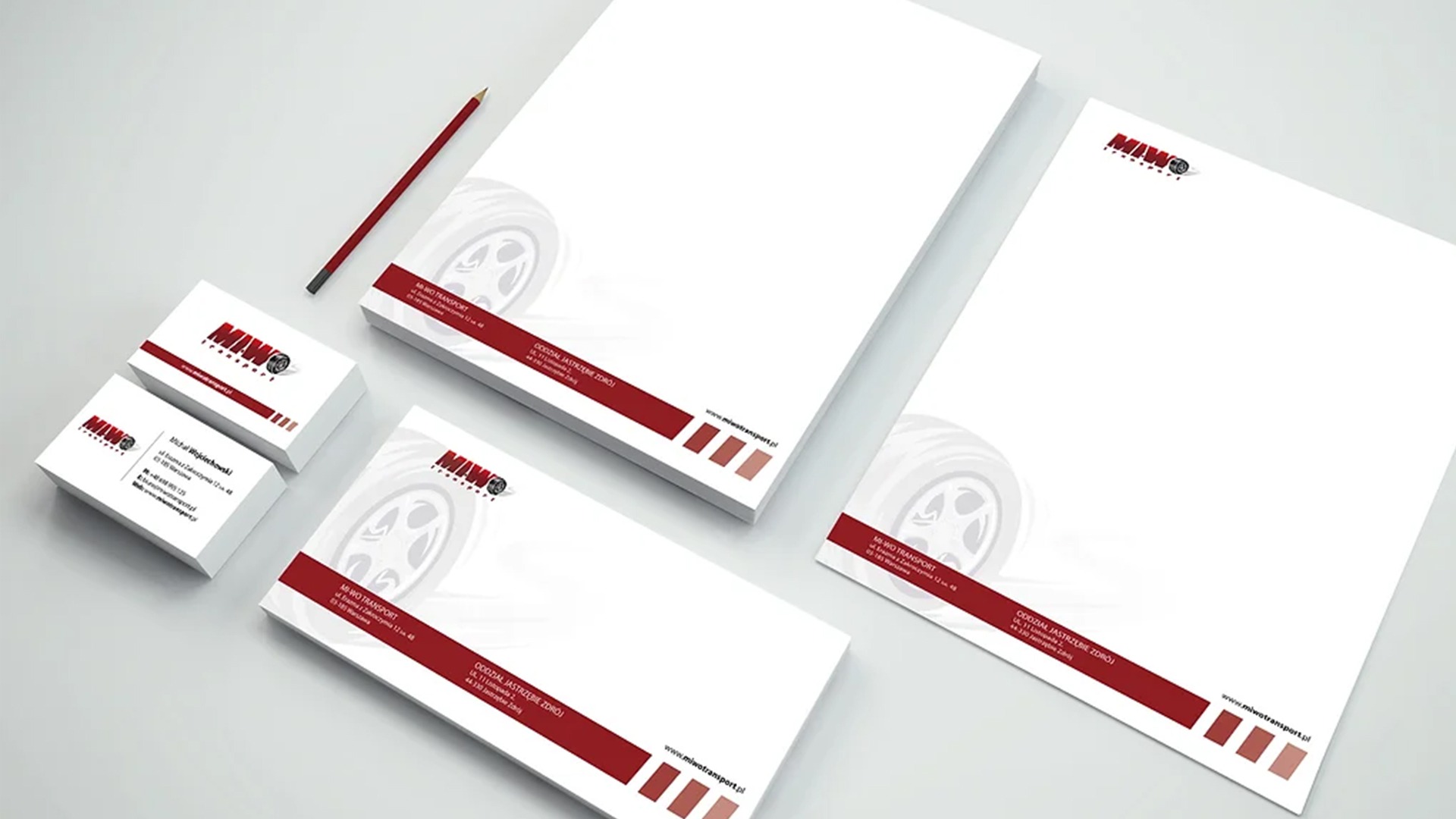Wizualizacja identyfikacji wizualnej firmy transportowej: wizytówki, papier firmowy i koperta z logo i danymi kontaktowymi, ułożone na jasnym tle, obok ołówka.