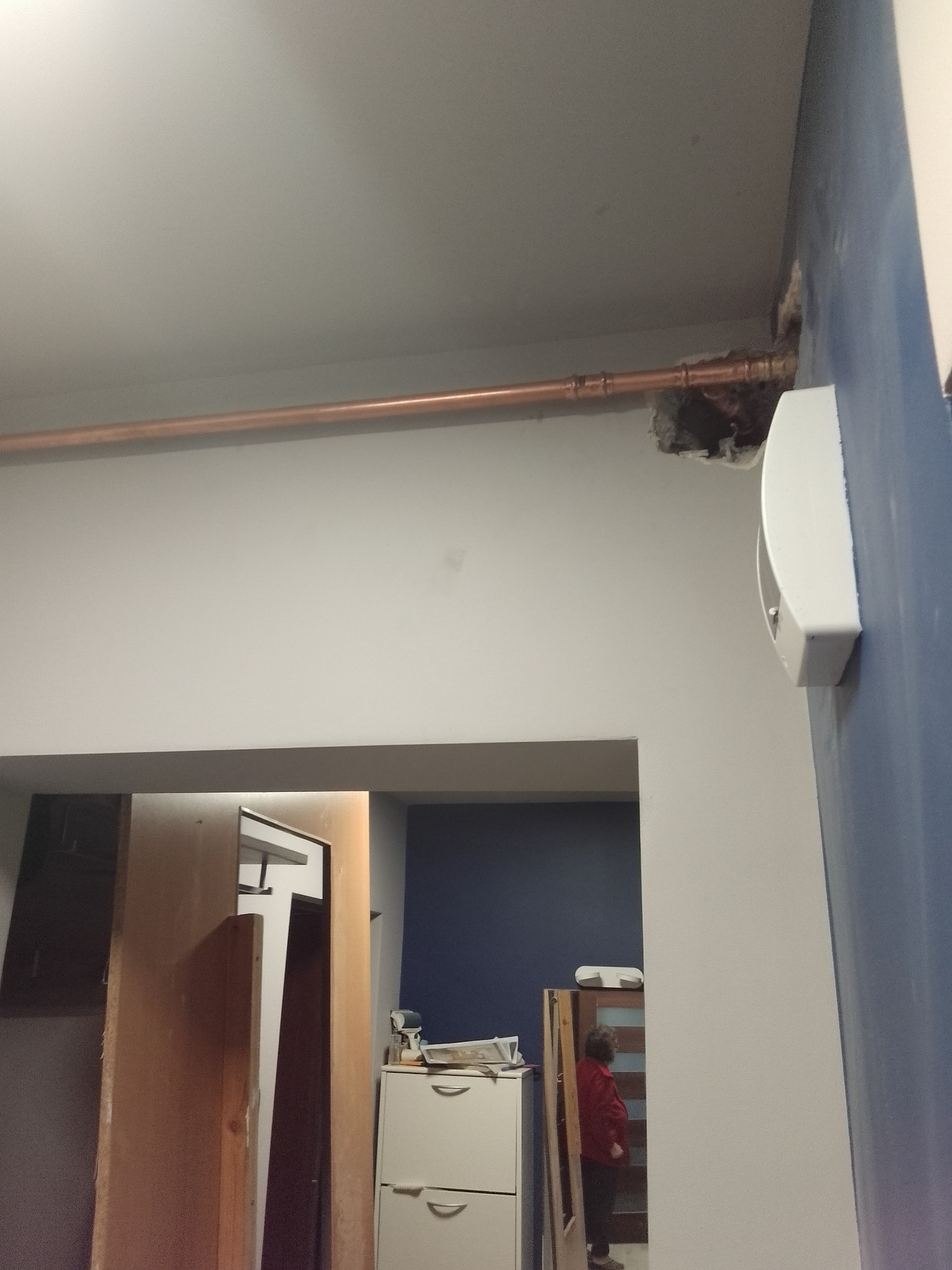Miedziana rura gazowa prowadzona pod sufitem w trakcie montażu, widoczne niedokładności wykończenia ściany i otwór w suficie.