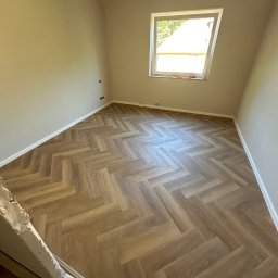 Zakład usług ogólno budowlanych Zalewski Sławomir - Pokój po remoncie z nowo ułożonymi panelami w jodełkę, widoczne listwy przypodłogowe i okno dachowe.