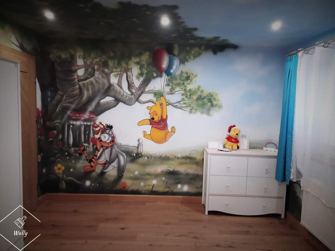 Pokój dziecięcy z ręcznie malowaną ścianą przedstawiającą Kubusia Puchatka, Tygryska i Kłapouchego pod drzewem z balonami, komoda z pluszowym Kubusiem Puchatkiem w czapce Mikołaja.