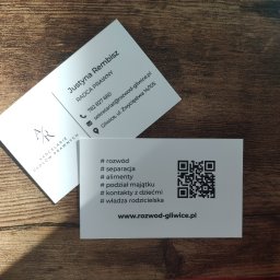Kancelaria Radcy Prawnego Justyna Rembisz - Dwie wizytówki radcy prawnego Justyny Rembisz na drewnianym tle, oferującej usługi związane z rozwodem, separacją, alimentami, podziałem majątku, kontaktami z dziećmi i władzą rodzicielską,...