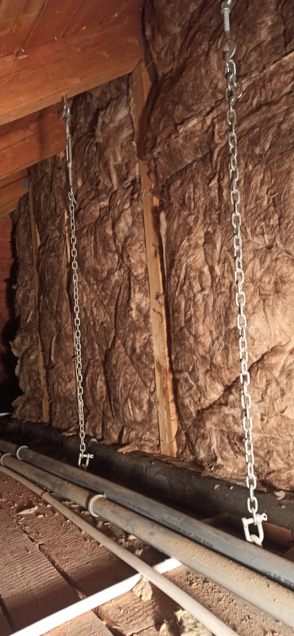 Ocieplenie poddasza wełną mineralną, zawieszone na łańcuchach, widoczne rury instalacyjne