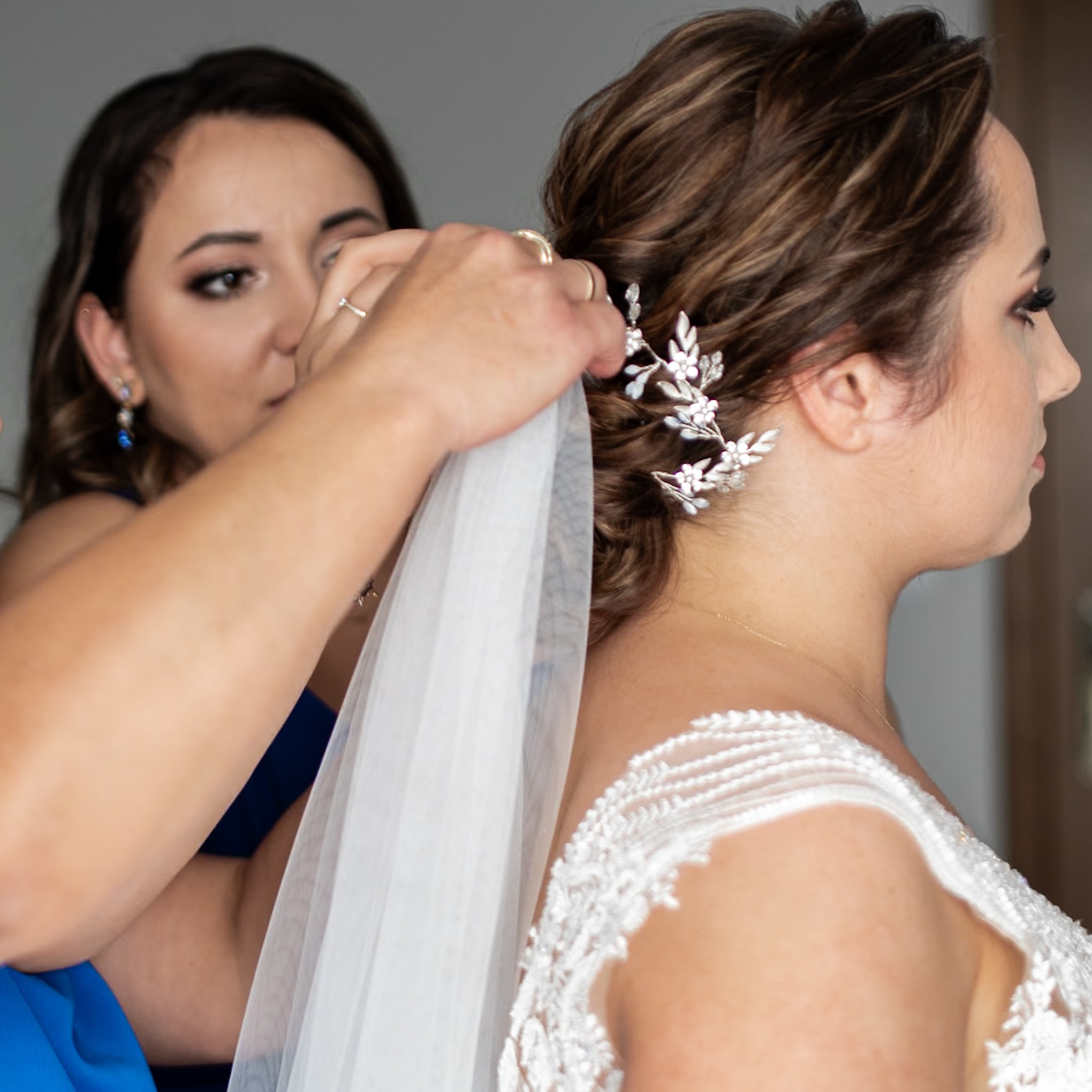 Fryzjerka z Wieruszowa poprawia welon pannie młodej, widoczna srebrna ozdoba we włosach i fragment koronkowej sukni.