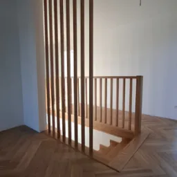 Nowoczesna drewniana balustrada schodowa z pionowymi szczeblami i podłogą w jodełkę, widok z góry.